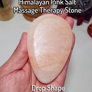 May include: A drop-shaped Himalayan pink salt massage therapy stone with a smooth, translucent surface featuring light orange and white mineral variations. The text Himalayan Pink Salt Massage Therapy Stone and Drop Shape is visible.