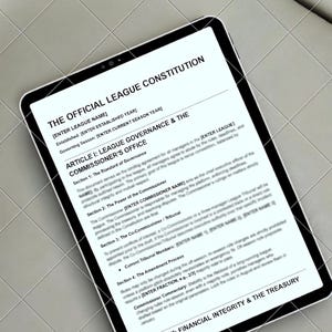 Könnte beinhalten: Ein digitales Tablet mit einem Dokument mit dem Titel "THE OFFICIAL LEAGUE CONSTITUTION". Das Dokument enthält Abschnitte über die Ligaführung, das Büro des Commissioners und die finanzielle Integrität. Das Tablet liegt auf einer hellgrauen Oberfläche.