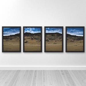 Puede incluir: Cuatro impresiones enmarcadas de paisajes. Cada impresión presenta una vista de una playa arenosa y colinas bajo un cielo azul con nubes. Los marcos son negros y se exhiben en una pared blanca.