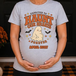 Peut inclure: Un t-shirt gris clair à manches courtes avec un motif de fantôme et le texte "EXPECTED TO HAUNT OUR HEARTS FOREVER APRIL 2027" en lettres orange et marron, entouré de petites chauves-souris, d'étoiles et de cœurs sur le devant du vêtement.
