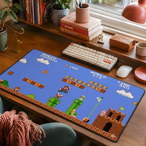 May include: A rectangular desk mat featuring a vibrant blue background with a pixelated Super Mario World 1-1 level design. The graphic includes Mario, green pipes, brick platforms, clouds, and a castle, with text displaying MARIO, 000500, and WORLD 1-1.