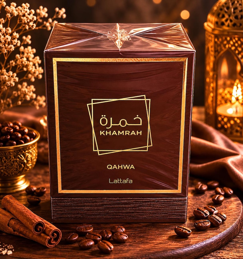May include: A rectangular dark brown perfume box wrapped in clear plastic. The front features gold text reading Khamrah, Qahwa, and Lattafa, along with Arabic script inside a gold square frame. The box has a textured base and a smooth top section.