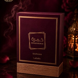 May include: A rectangular deep burgundy perfume box with a textured gold base. The front features gold-colored text reading Khamrah and Dukhan, along with the brand name Lattafa, enclosed in a gold square frame. The top left corner displays a logo.