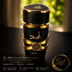 Pode incluir: Um frasco de perfume cil&iacute;ndrico preto e dourado com tampa triangular, apresentando caligrafia &aacute;rabe e o texto ASAD e Lattafa. O frasco inclui uma faixa central dourada com um emblema circular. O texto na imagem indica 100ml Eau de Parfum.