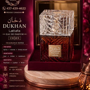 May include: A square glass perfume bottle with a textured, amber-colored base and a clear, faceted crystal-style cap. The bottle features a gold label with the text Khamrah Dukhan Lattafa. It is displayed inside an open, dark red velvet-lined box.