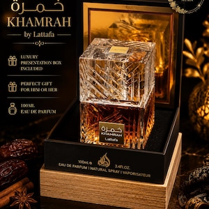 May include: A square glass perfume bottle with a textured, faceted surface containing amber-coloured liquid, labelled Khamrah by Lattafa. The bottle is housed in a black and gold presentation box, with 100ml and 3.4 fl. oz. printed on the base.