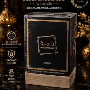 May include: A black rectangular perfume box labelled Khamrah by Lattafa with gold text and accents. The box is wrapped in clear plastic and sits on a light brown wooden base. The text reads Eau de Parfum, Natural Spray, and 100ml.
