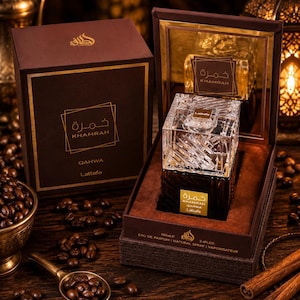 May include: A Lattafa Khamrah Qahwa eau de parfum bottle with a clear, faceted glass cap and a dark brown base, presented in an open brown box. The label reads Khamrah Qahwa Lattafa, with 100ml and 3.4 fl oz printed on the box edge.