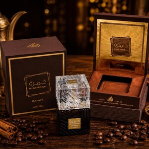 May include: A Lattafa Khamrah Qahwa perfume bottle with a clear, textured glass cap and a dark base, accompanied by its brown and gold presentation box. The box features the text Khamrah Qahwa and Lattafa, with a 100ml and 3.4 fl oz label.