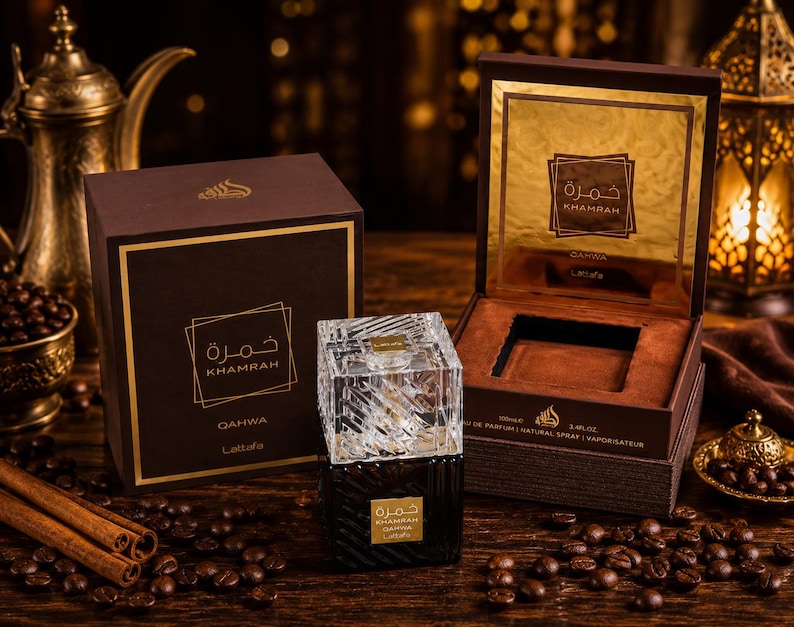 May include: A Lattafa Khamrah Qahwa perfume bottle with a clear, textured glass cap and a dark base, accompanied by its brown and gold presentation box. The box features the text Khamrah Qahwa and Lattafa, with a 100ml and 3.4 fl oz label.
