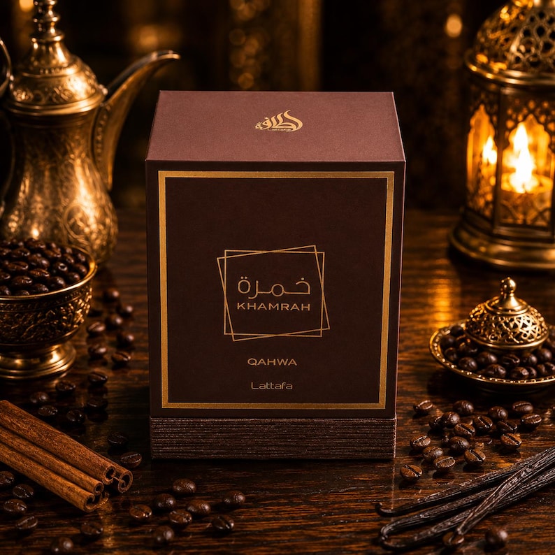 May include: A square brown perfume box with gold lettering featuring the text Khamrah Qahwa Lattafa. The box is centered with a gold border and a geometric square design. The top of the box displays an Arabic script logo in gold ink.