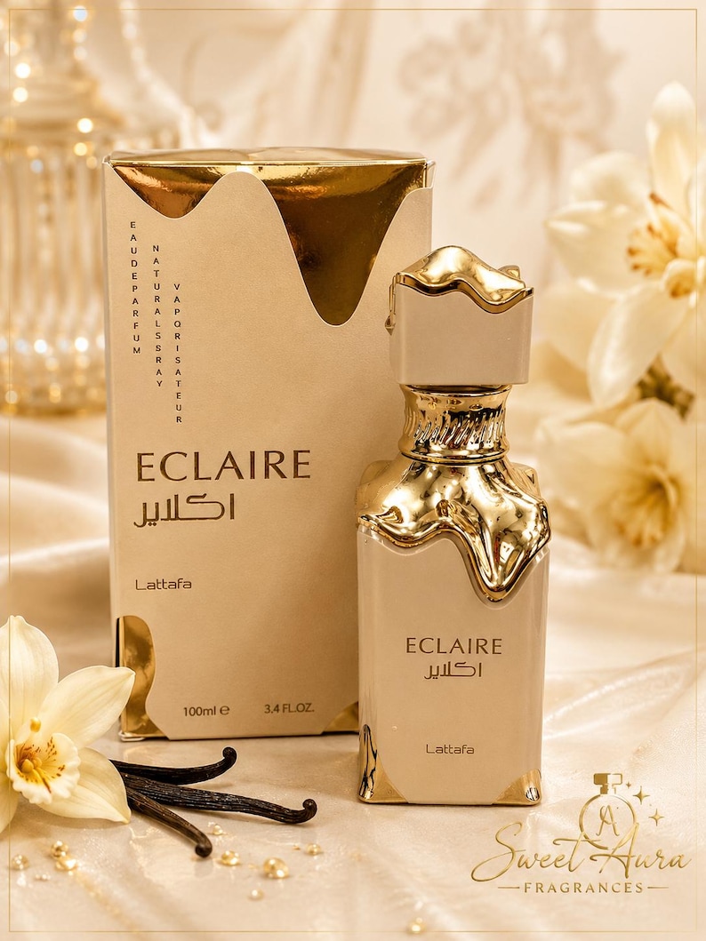 May include: A beige perfume bottle and its matching rectangular box, both labeled Eclaire Lattafa. The bottle and box feature a metallic gold drip design at the top. The packaging displays 100ml and 3.4 fl. oz. text. The bottle has a gold cap.