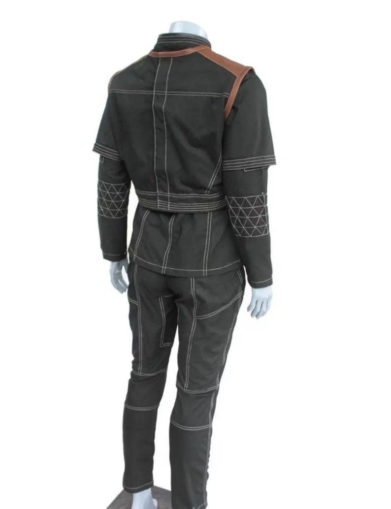 May include: A dark green two-piece outfit with white stitching and brown shoulder accents. The jacket has a high collar and short sleeves. The pants have a fitted design. The outfit is displayed on a mannequin.