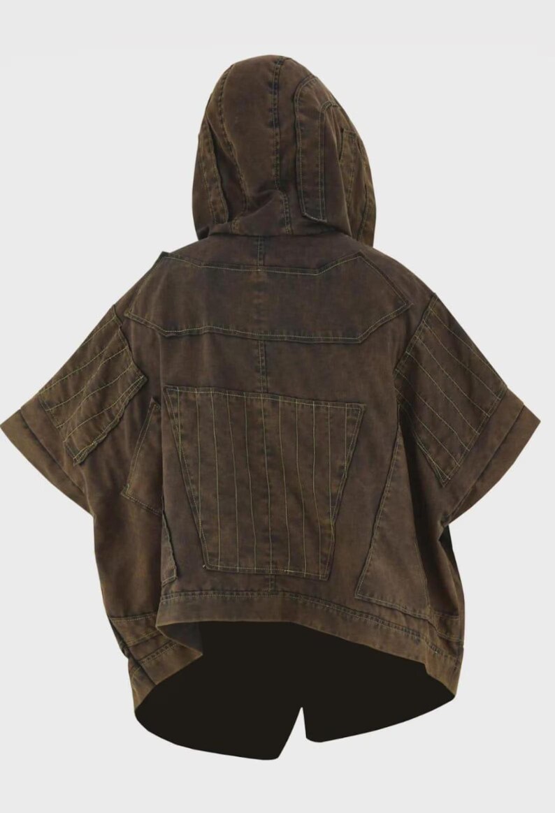 Puede incluir: Chaqueta con capucha marr&oacute;n con mangas cortas. La chaqueta presenta m&uacute;ltiples bolsillos y detalles de costura verticales en la espalda y las mangas. La prenda tiene un corte asim&eacute;trico &uacute;nico y un ajuste relajado.