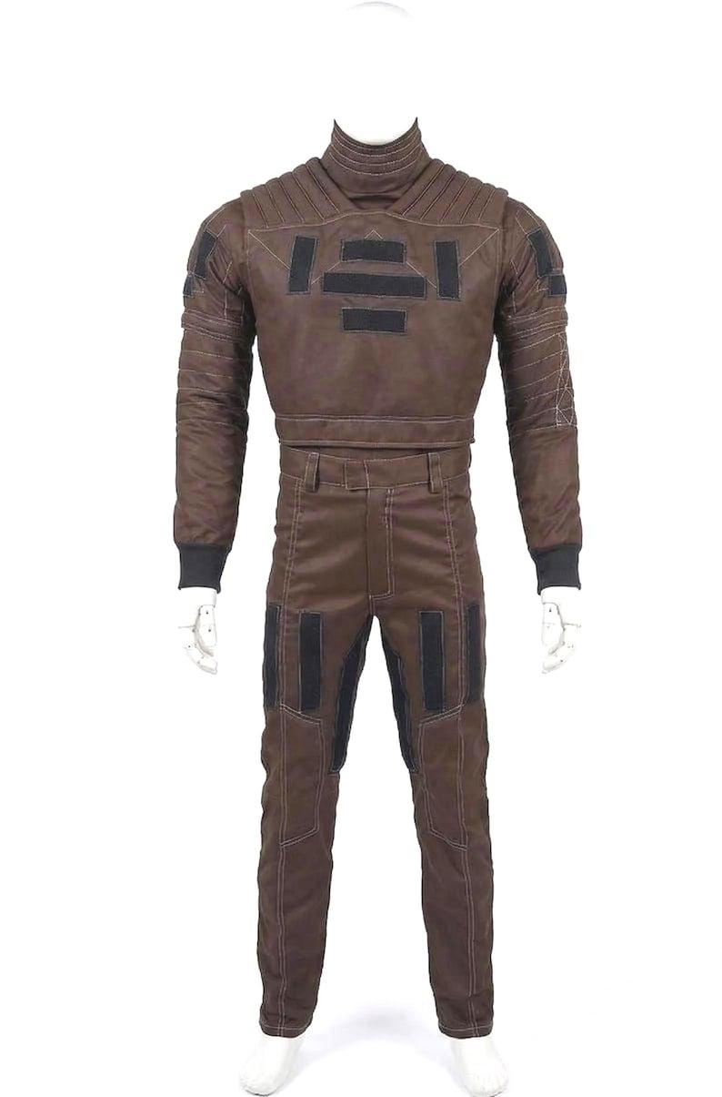May include: Brown jumpsuit with black accents, displayed on a mannequin. The outfit features a high collar, long sleeves, and a two-piece design. The pants have pockets and the jacket has decorative panels. The overall style is reminiscent of a space suit.