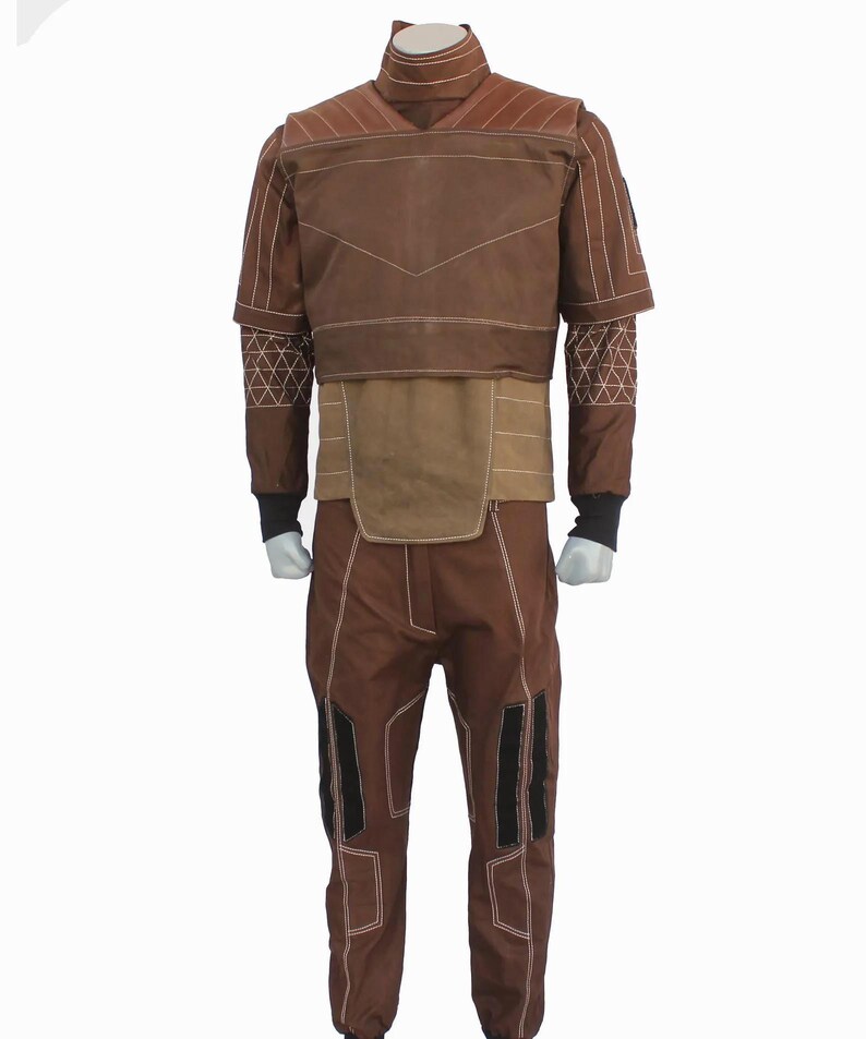 May include: A brown long-sleeved shirt and matching pants set featuring a high collar, white topstitching, and geometric patterns on the sleeves. The shirt has a layered chest panel, while the pants include black rectangular accents on the legs.