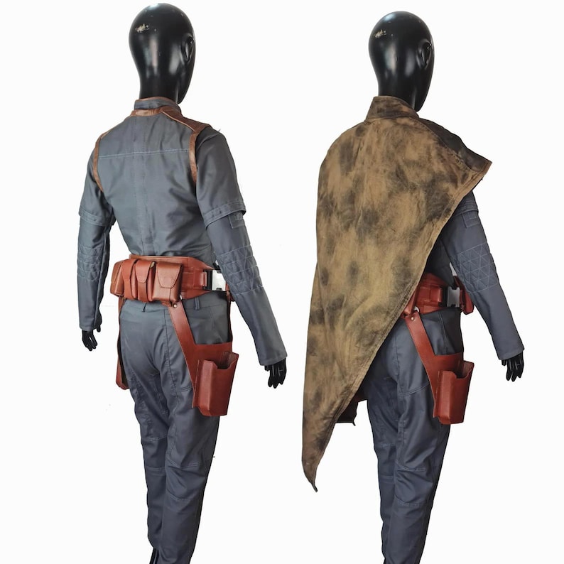 May include: A gray long-sleeved shirt and pants set worn with a brown leather utility belt featuring multiple pouches and a holster. One view includes a distressed brown cape draped over the shoulder, while the other shows the belt and shirt details.