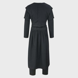 May include: A black, two-piece outfit featuring a long-sleeved top with shoulder detailing and a skirt-like bottom. The outfit appears to be made of a dark fabric, possibly denim or a similar material. The back view of the outfit is shown.