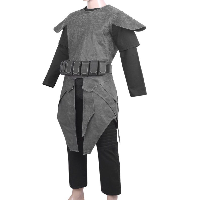 May include: A dark gray textured tunic with shoulder pauldrons and a matching waist belt featuring multiple rectangular pouches. The garment is worn over a black long-sleeved shirt and black trousers with ribbed detailing on the upper thigh area.