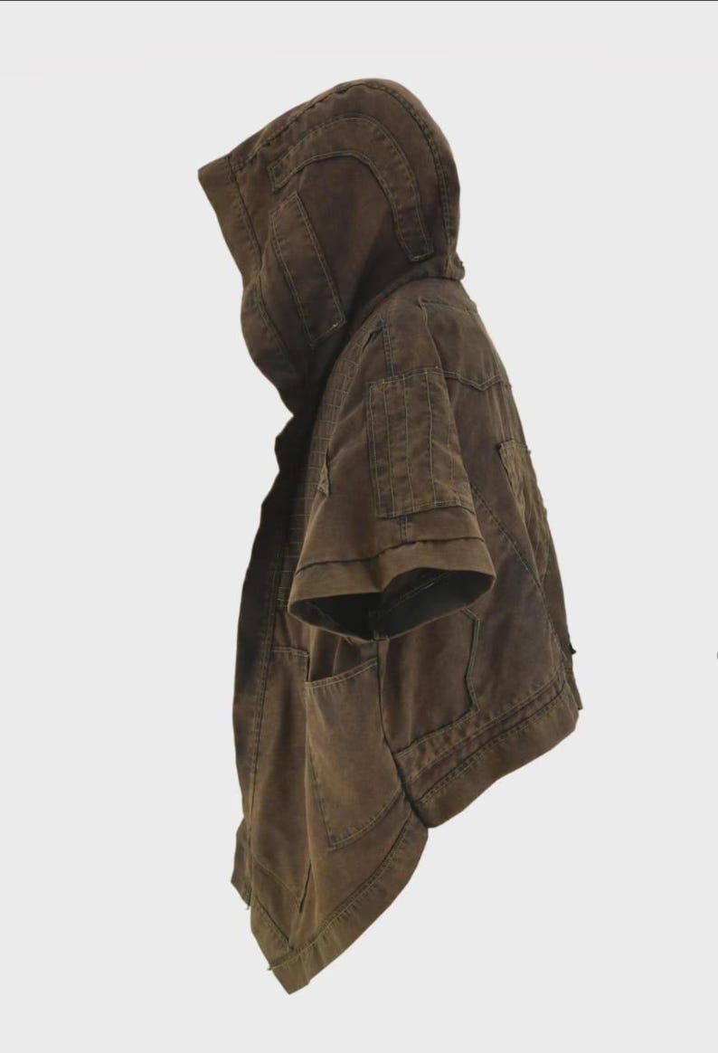 Puede incluir: Chaqueta con capucha marr&oacute;n con mangas cortas. La chaqueta tiene m&uacute;ltiples bolsillos y una capucha estructurada. La tela parece ser un material duradero, posiblemente similar a la lona. La chaqueta tiene un dise&ntilde;o utilitario.