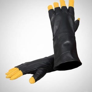 May include: A pair of fingerless gloves featuring a black main body and contrasting yellow fingertips. The gloves have a long cuff design that extends past the wrist, with exposed fingers and a thumb section finished in bright yellow leather.