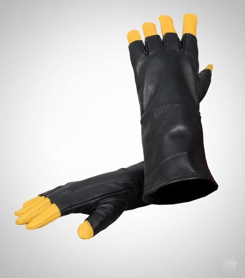 May include: A pair of fingerless gloves featuring a black main body and contrasting yellow fingertips. The gloves have a long cuff design that extends past the wrist, with exposed fingers and a thumb section finished in bright yellow leather.
