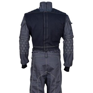May include: A gray racing suit with a black upper back panel and white stitching. The suit has geometric patterns on the sleeves and a zipper closure. The suit has black cuffs and a belt loop.