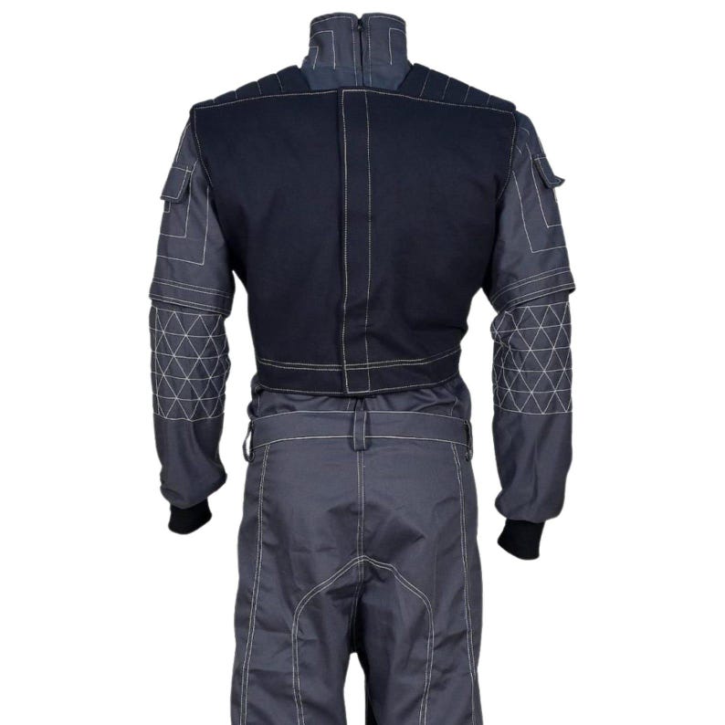 May include: A gray racing suit with a black upper back panel and white stitching. The suit has geometric patterns on the sleeves and a zipper closure. The suit has black cuffs and a belt loop.