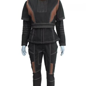 May include: Black two-piece outfit with brown accents and white stitching. The jacket has a high collar, short sleeves, and a peplum waist. The pants have brown patches on the knees. The outfit is displayed on a mannequin.