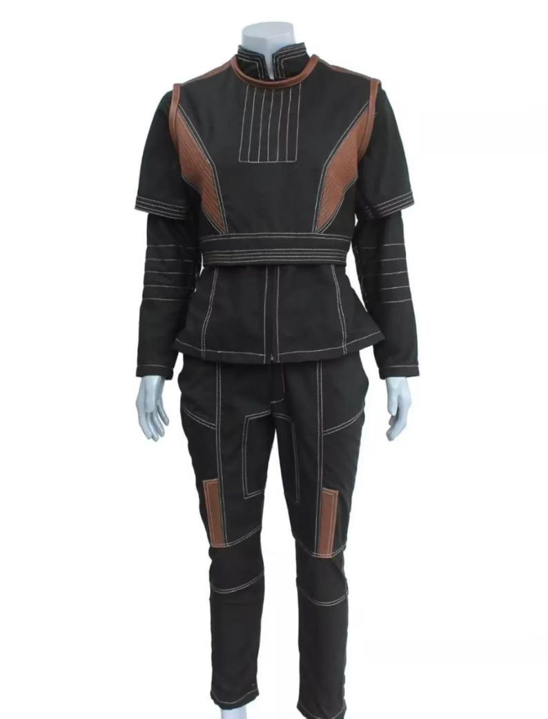 May include: Black two-piece outfit with brown accents and white stitching. The jacket has a high collar, short sleeves, and a peplum waist. The pants have brown patches on the knees. The outfit is displayed on a mannequin.