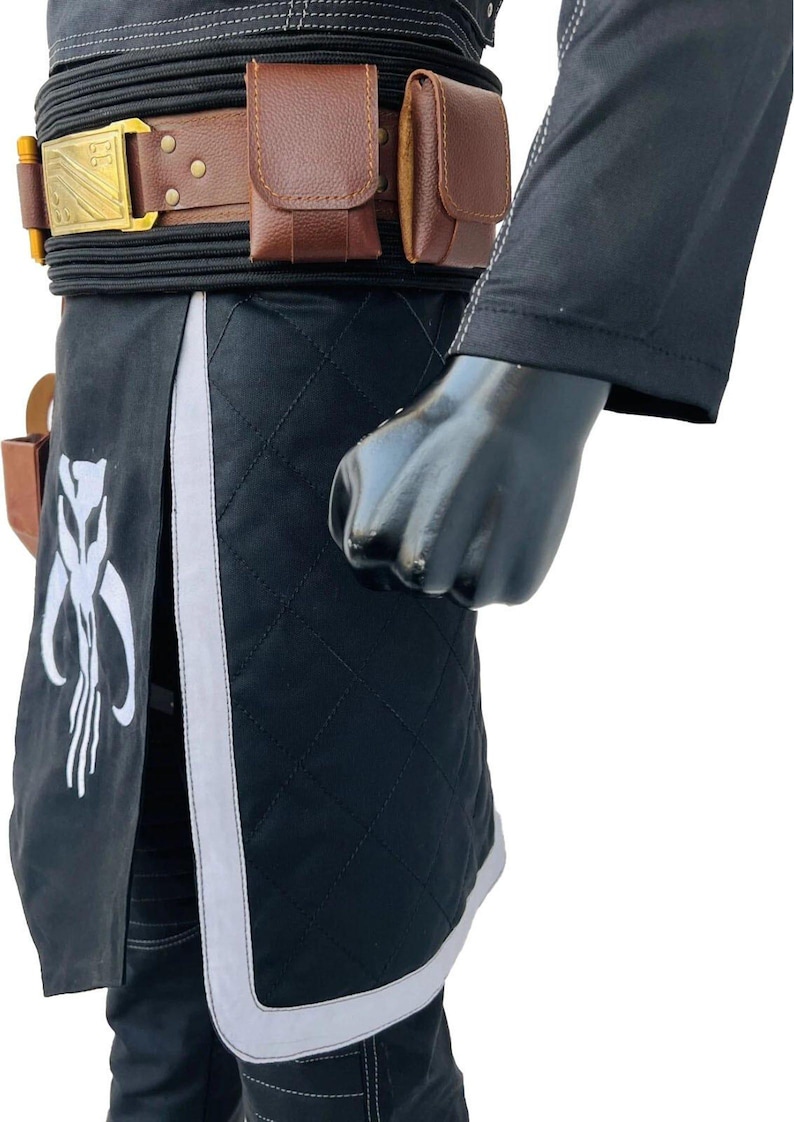 May include: Black quilted fabric costume with white accents and a brown leather belt. The belt has a gold buckle and brown pouches. A white emblem is on the black fabric.