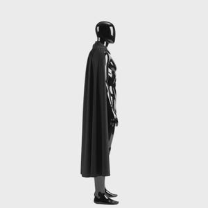 May include: A black mannequin wearing a black cape. The mannequin is glossy and has a smooth, reflective surface. The cape is long and drapes down the mannequin's back. The mannequin is wearing black shoes.