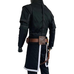 May include: Black costume with white stitching and accents. The outfit includes a long coat with a quilted design, a brown belt with pouches, and a holster. The costume has a high collar and long sleeves.