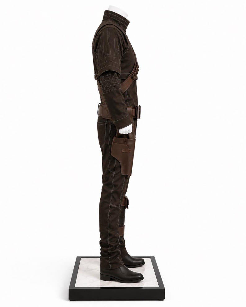 May include: A brown costume with a high collar, shoulder straps, and a belt. The outfit includes a jacket, pants, and boots. A holster is attached to the belt. The costume is displayed on a white mannequin.