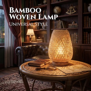 May include: A bamboo woven lamp with a warm glow sits on a round wicker table. The lamp has a woven design and is labeled "BAMBOO WOVEN LAMP UNIVERSAL STYLE". A leather-bound journal and magnifying glass are also on the table.