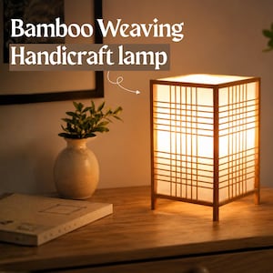 Puede incluir: Una lámpara de mesa rectangular con marco de madera clara y un tejido de bambú con patrón de rejilla sobre una pantalla blanca translúcida. La lámpara emite una luz cálida y muestra el texto Bamboo Weaving Handicraft lamp.