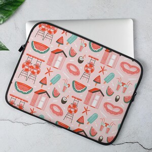 May include: A pink laptop sleeve with a repeating pattern of beach-themed illustrations. The design includes lifeguard stands, watermelon slices, popsicles, and drink glasses. The sleeve has a black zipper and trim.