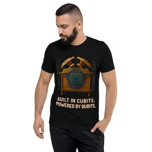 May include: Dark gray t-shirt featuring a graphic of a golden chest with a circuit board design and two eagle figures. The text "BUILT IN CUBITS. POWERED BY QUBITS." is printed below the graphic.