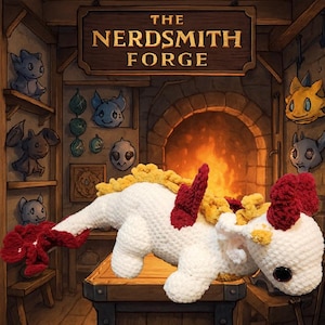 Puede incluir: Un dragón de ganchillo blanco hecho a mano con detalles rojos y amarillos. El dragón está sobre una superficie de madera frente a una chimenea. El letrero de arriba dice "THE NERDSMITH FORGE".