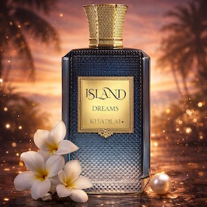 May include: A rectangular perfume bottle with a gold cap and a gold label that reads "ISLAND DREAMS" and "KHADLAJ.". The bottle is blue and has a textured pattern. White flowers and a pearl are in the foreground.