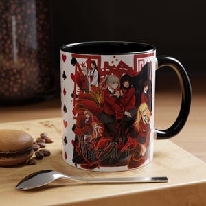 May include: White ceramic mug with a black interior and handle. The mug features a colorful anime-style illustration with red and black accents, and Japanese text. The design includes playing card suit symbols.