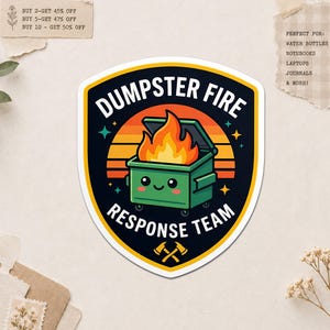 May include: A sticker with a black and yellow border features a green dumpster on fire with the text "DUMPSTER FIRE RESPONSE TEAM." The background has a sunset design. The sticker is suitable for water bottles, notebooks, laptops, and journals.