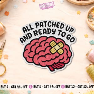 May include: Embroidered patch featuring a pink brain with a bandage, and the text "ALL PATCHED UP AND READY TO GO" in white. The patch has a black border. Decorative elements are visible in the background.