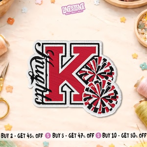 May include: An embroidered patch featuring a large red letter K with a white border. The word Knights is written in black script along the left side of the letter. Two round pom-poms with red, black, and white strands are attached to the right side.
