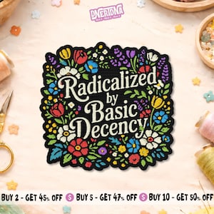 May include: Black patch with the text "Radicalized by Basic Decency" in white script, surrounded by a floral border of red, yellow, blue, and purple flowers. The patch has a black border and is likely an iron-on or sew-on patch.