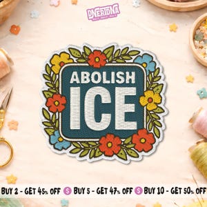 May include: Embroidered patch with the words "ABOLISH ICE" in white on a teal background, surrounded by a floral wreath of red, yellow, and blue flowers. The patch has a white border.