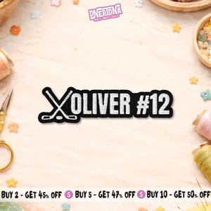 May include: A black and white embroidered patch featuring two crossed hockey sticks on the left, followed by the name OLIVER and the number #12 in a bold, sans-serif font. The design is outlined in black thread on a white background.
