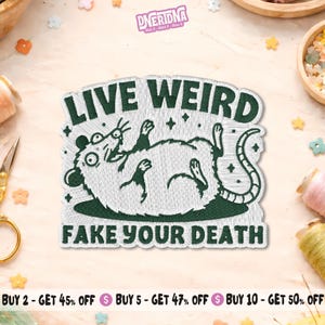 May include: Embroidered patch with the text "LIVE WEIRD FAKE YOUR DEATH" in dark green. The patch features a cartoon rat lying on its back. The patch has a white background and a stitched design.