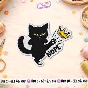 Peut inclure: Écusson brodé représentant un chat noir aux yeux jaunes repoussant une couronne dorée. Le mot "NOPE" est écrit en dessous. Le patch a une bordure blanche et est destiné aux vêtements ou accessoires.