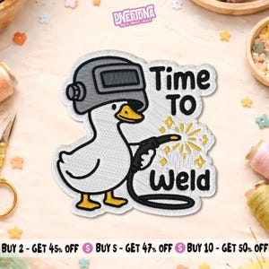 May include: An embroidered patch featuring a white duck wearing a grey welding helmet and holding a welding torch. The design includes yellow sparks and the black text Time TO WELD. The patch has a white border and a textured fabric appearance.